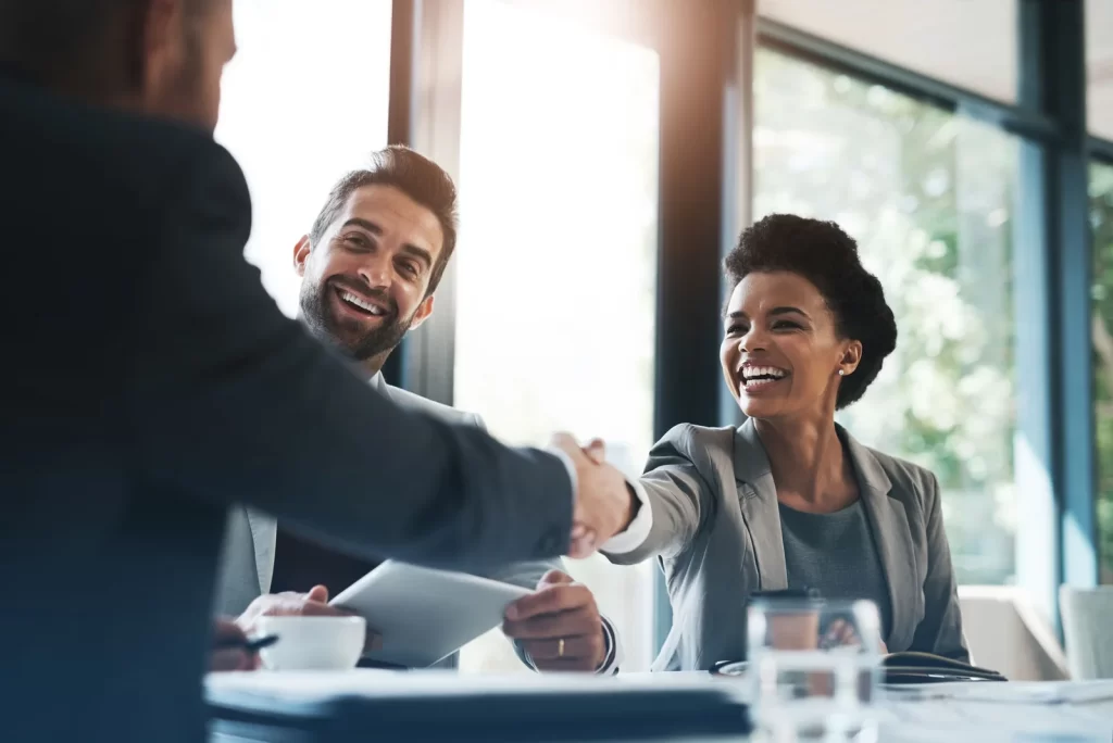 Two professionals shaking hands across a meeting table