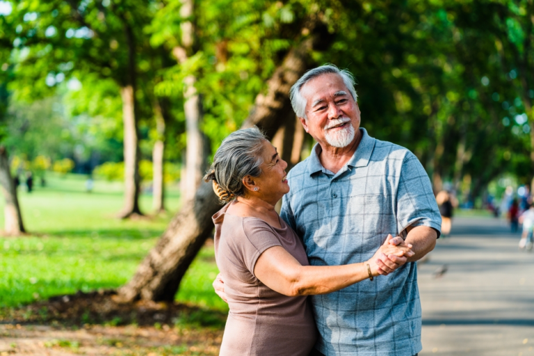 A senior couple dancing together in a park